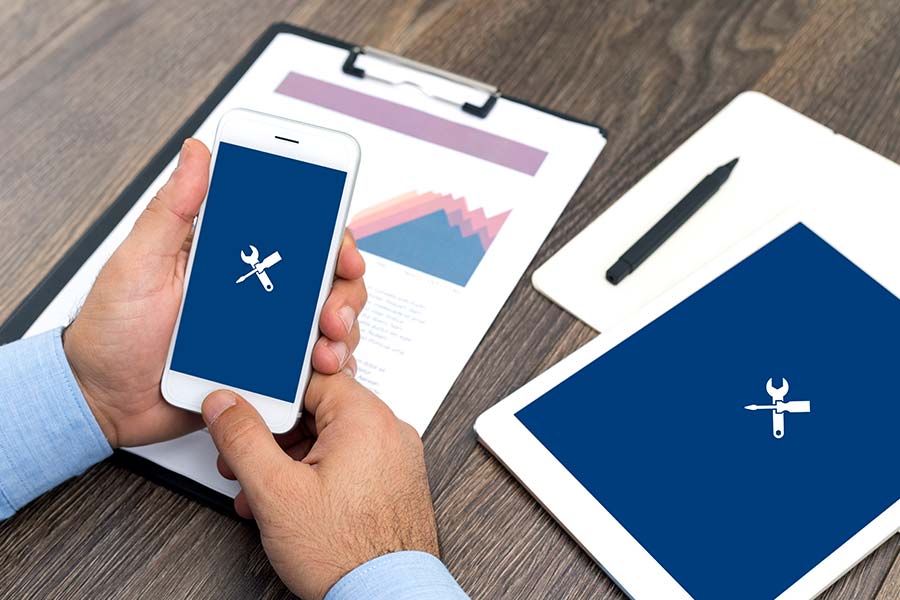 Das Bild zeigt zwei Hände, die ein Handy halten auf dessen Display ein Werkzeug-Icon zu sehen ist.
