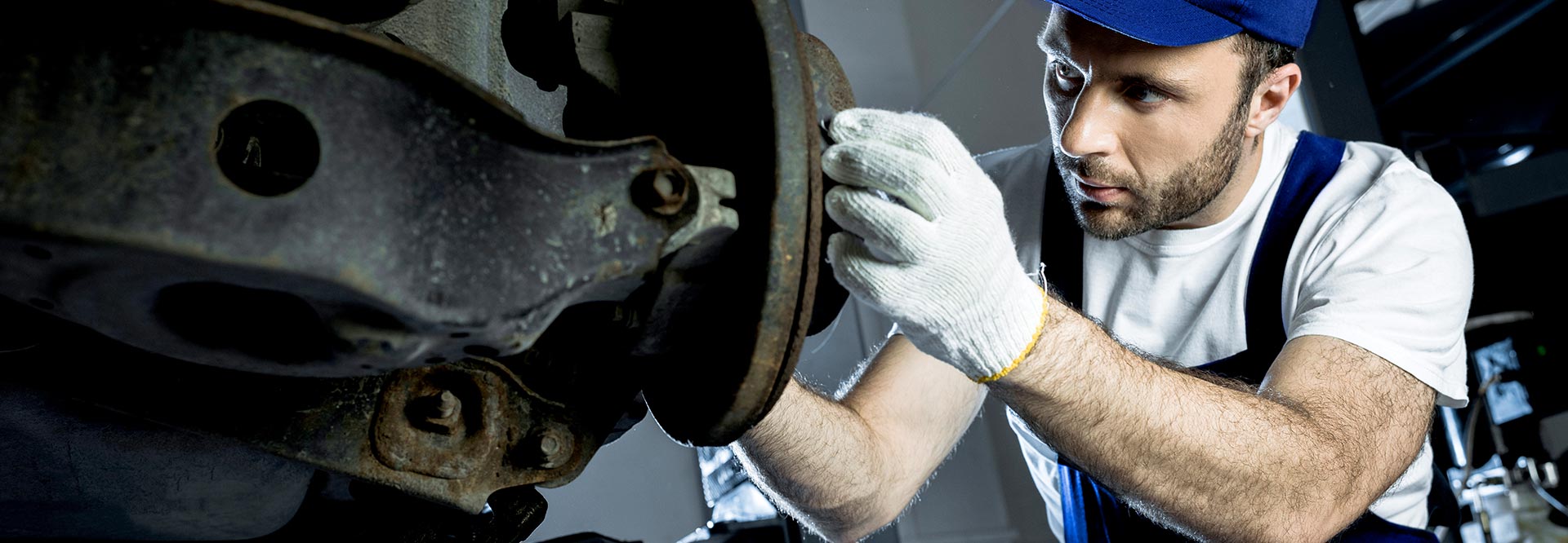 The picture shows a car mechanic repairing a vehicle at the garage.