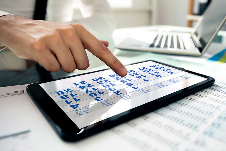 The picture shows one hand tapping the calendar on a tablet PC.