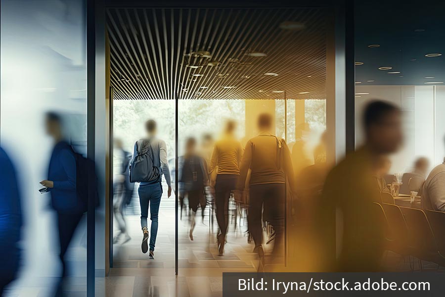 The image shows the blurred silhouettes of office employees moving around a company building.