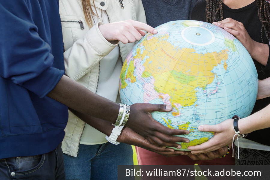 A globe is held by different hands.